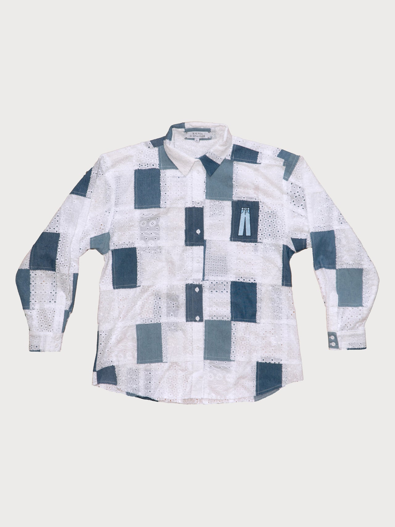 A long sleeve patchwork shirt with white and blue colors, featuring a front button closure and buttoned cuffs.